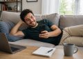Korepetytor leży na kanapie i sprawdza grafik zajęć na telefonie, zarządzając korepetycjami online w aplikacji dla korepetytorów Reservis